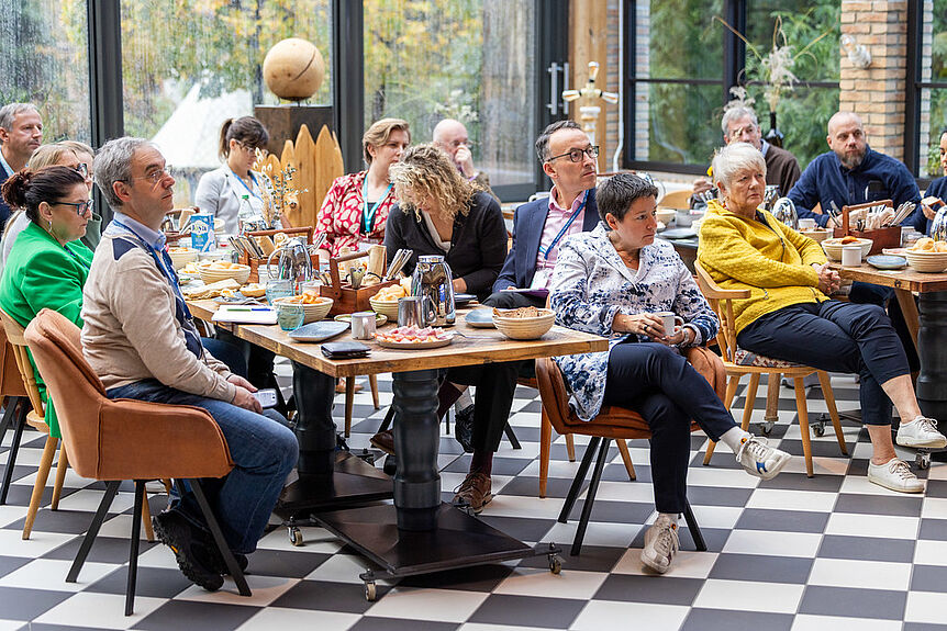 Group of people sitting at a table listening to a presentation